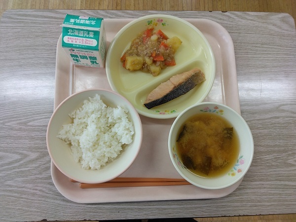 給食（「ゆめぴりか」（有機栽培米）、お味噌汁（有機栽培大豆使用味噌）、鮭塩焼き、ジャガイモそぼろ煮、牛乳）